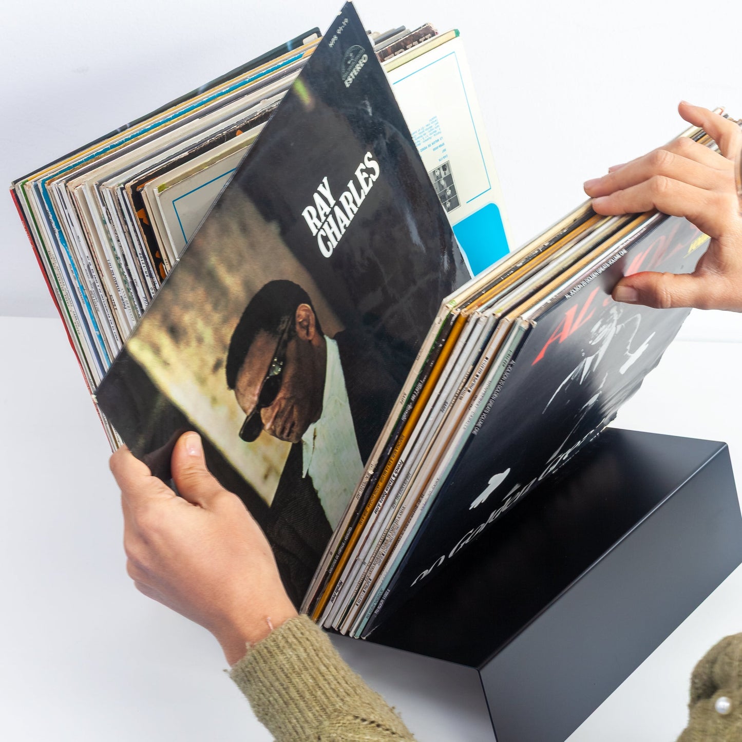 Collector flipping through 50 vinyl records organized in Vinyl Break powder-coated steel stand