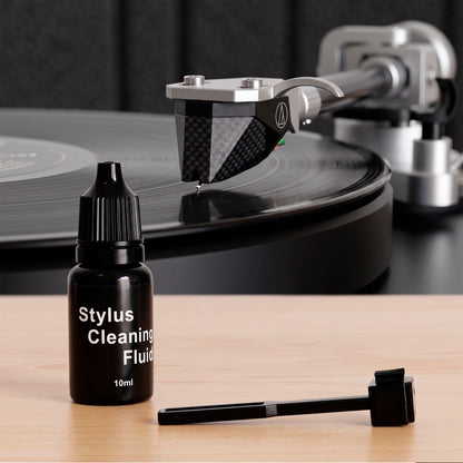 Stylus cleaning fluid (10 ml) and stylus brush from the Vinyl Record Cleaning Kit next to a turntable