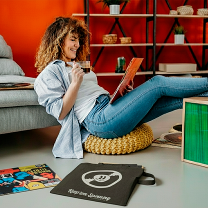 mujer sentada en el suelo tomando café con un disco de vinilo en las manos