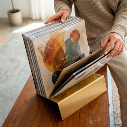 Hands flipping through vinyl records stored in gold Vinyl Break stand on wooden credenza