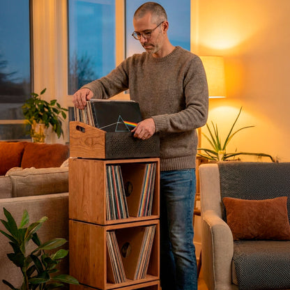 Manos sacando un disco de vinilo de una caja organizadora de madera, almacenamiento vertical para vinilos