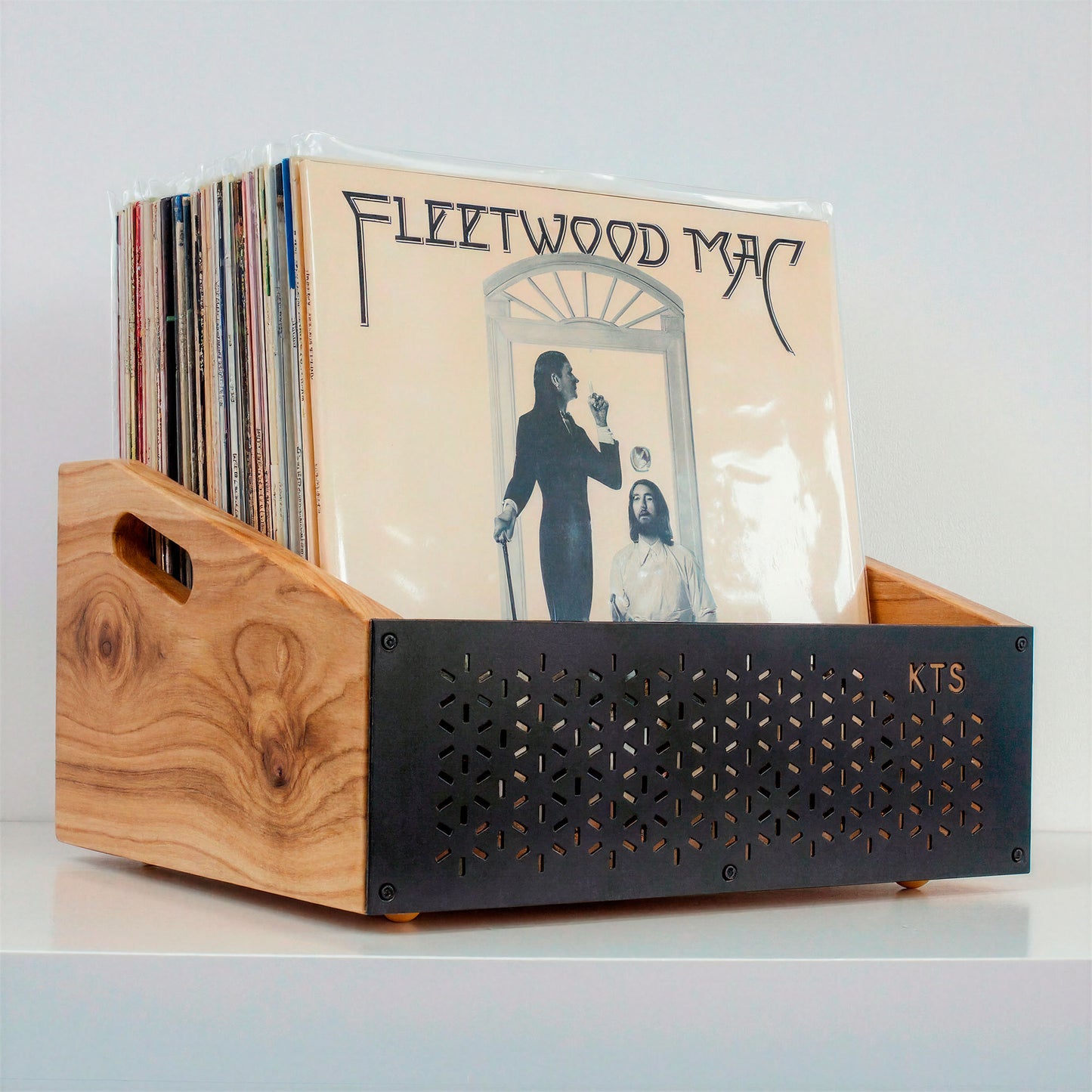 Hombre eligiendo un vinilo junto a tocadiscos y soporte de vinilos de madera en salón acogedor