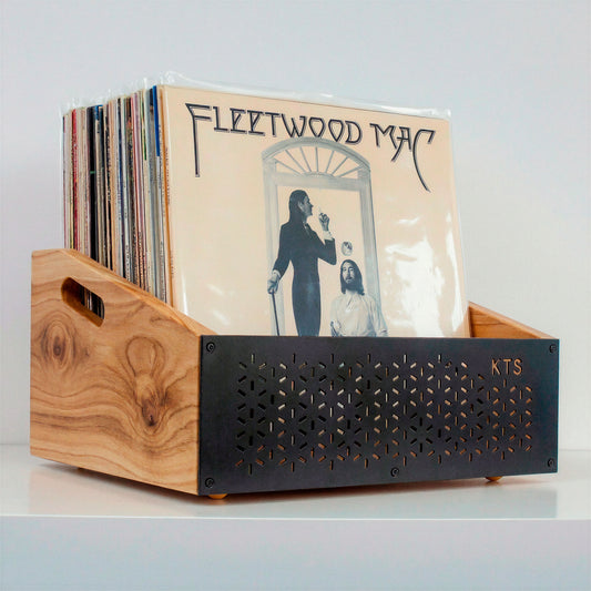 Hombre eligiendo un vinilo junto a tocadiscos y soporte de vinilos de madera en salón acogedor